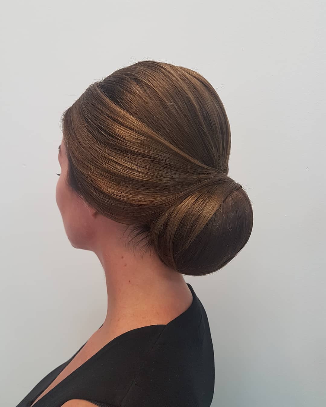 Strakke lage knot in donkerblond haar, van opzij