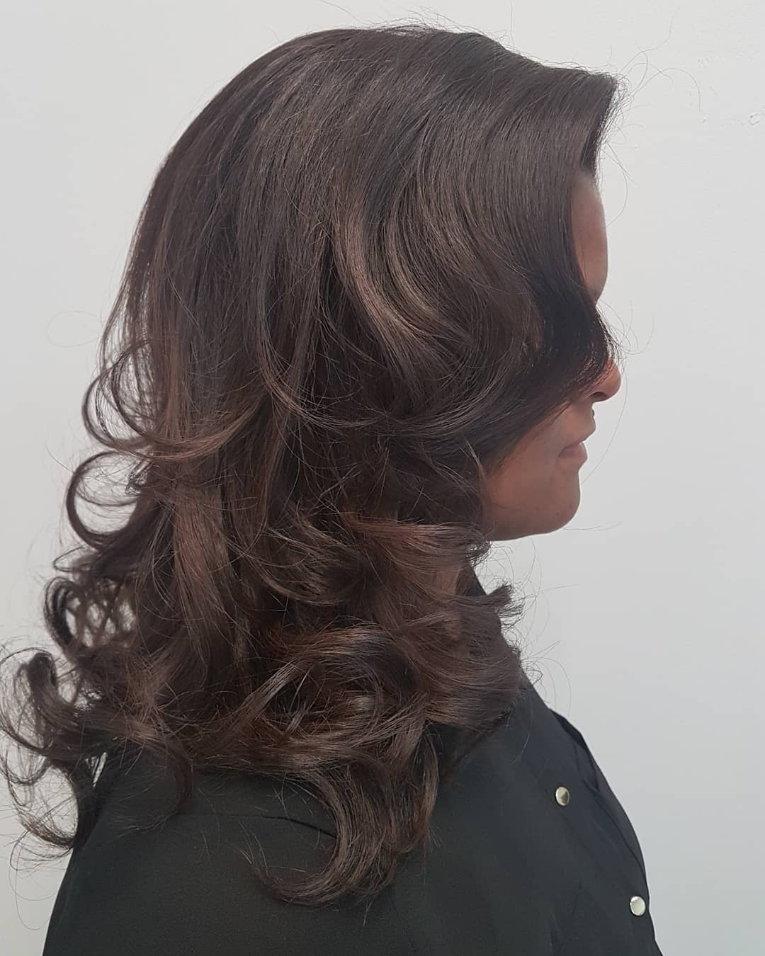 Donkerbruin haar met volume en grote krullen, van opzij