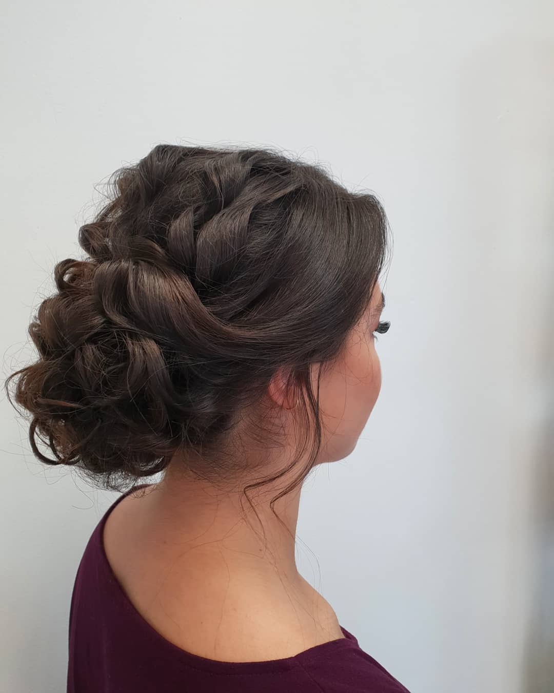 Gevlochten opgestoken kapsel in donker haar, van opzij